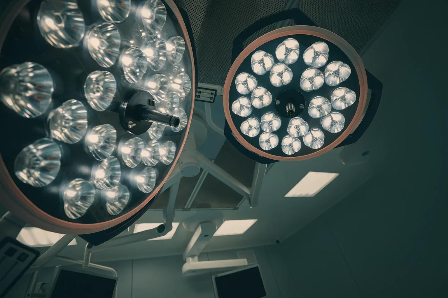Two surgical lights seen from below, switched on in an operating theatre.